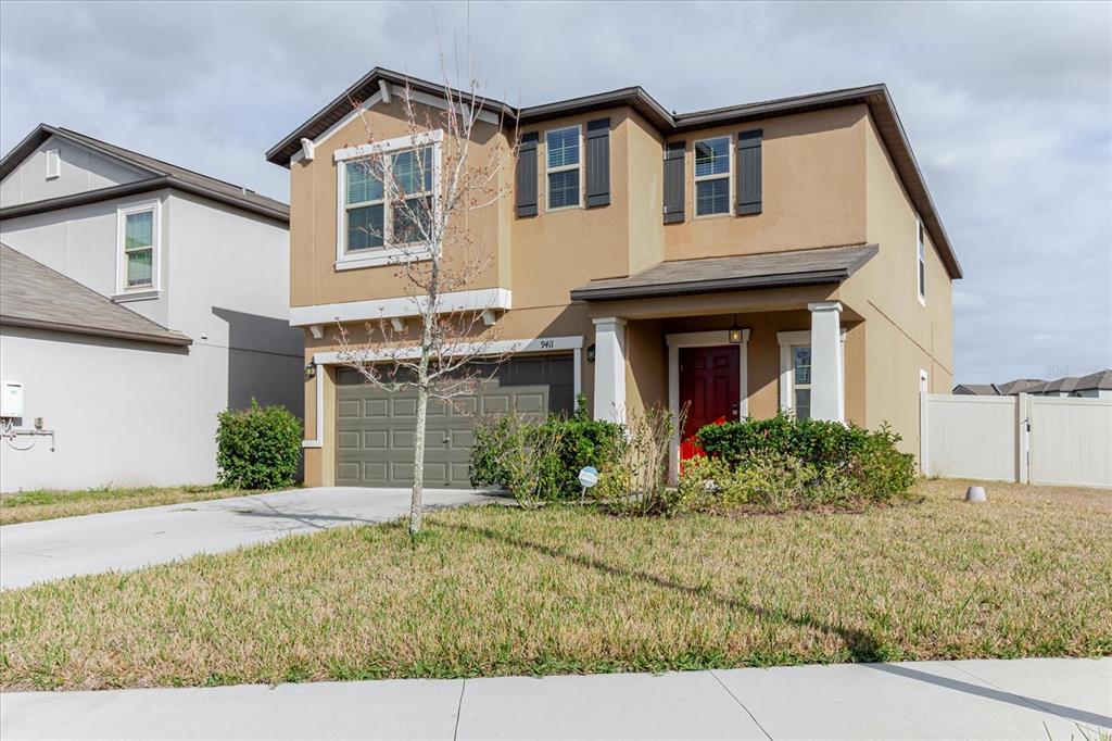 A two-story tan house with a two-car garage and a red front door — 9411 LEMON DROP LOOP, SUN CITY CENTER, FL