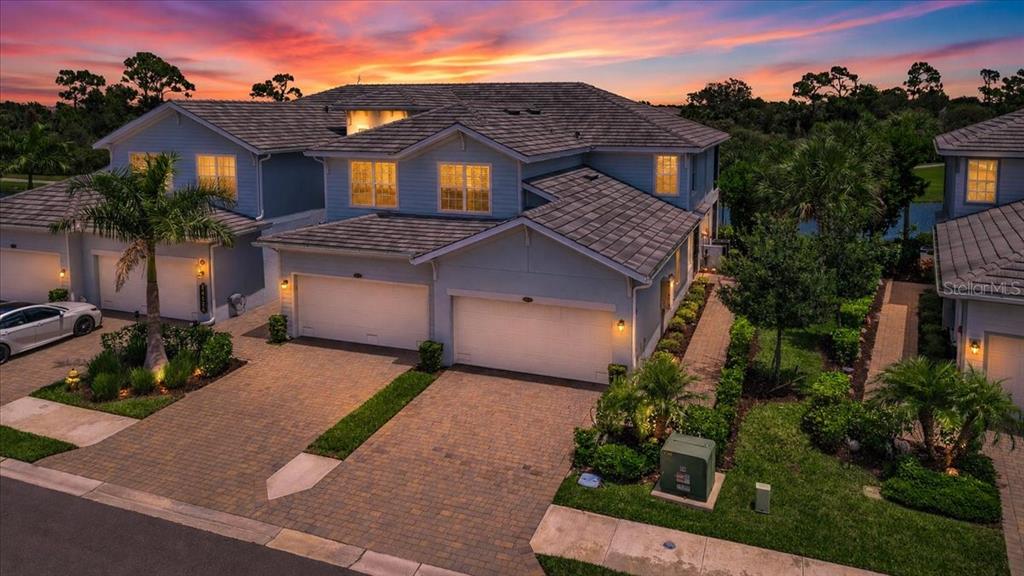 An aerial view of a two-story residential building with a paved driveway and sunset sky — 14120 POPPY FIELD LOOP UNIT 3812, PUNTA GORDA, FL