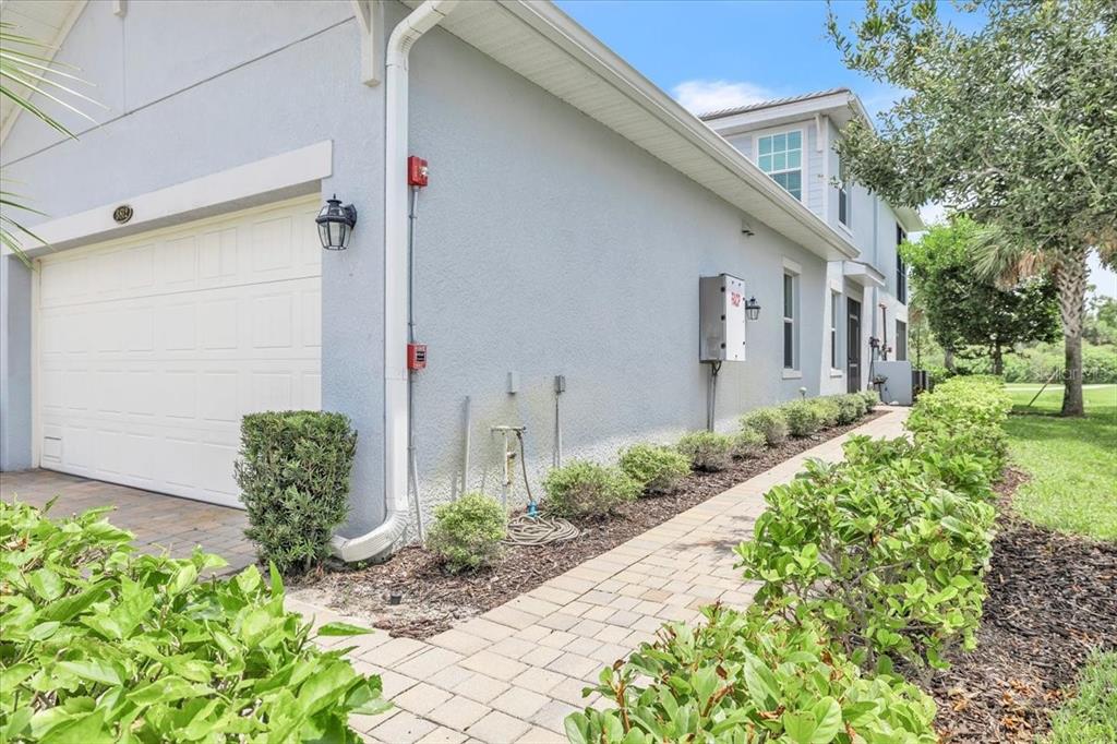 A paved walkway leads along the side of a light blue house with a garage — 14120 POPPY FIELD LOOP UNIT 3812, PUNTA GORDA, FL