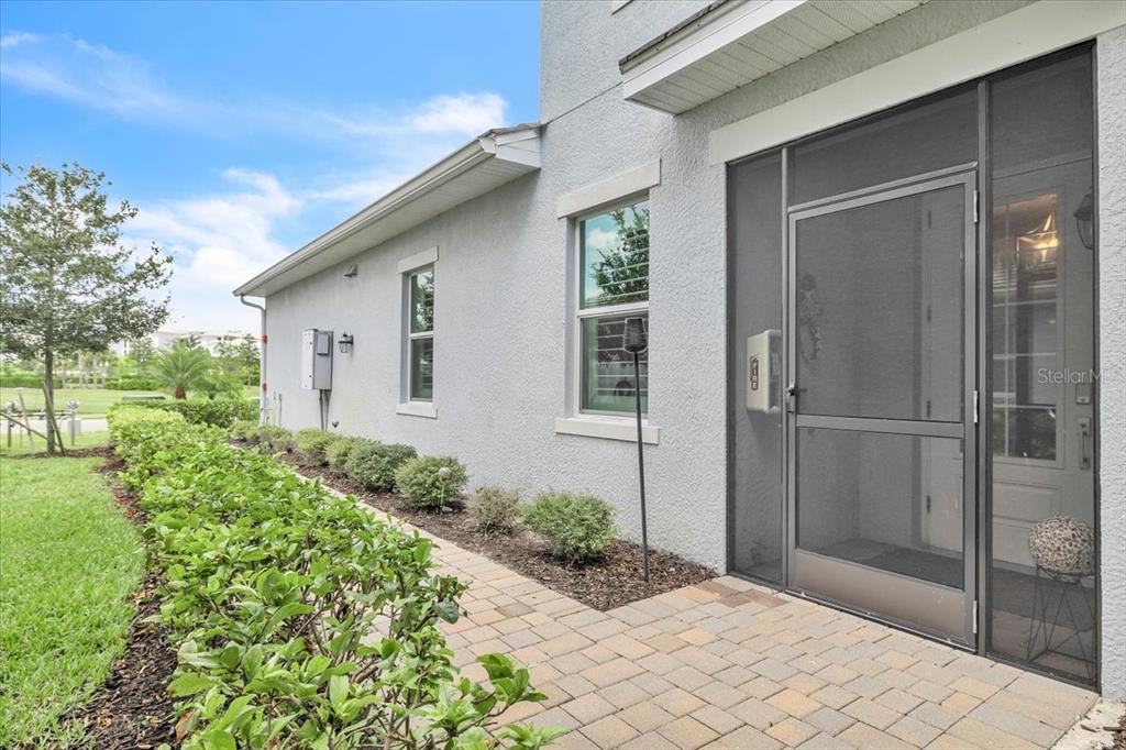 A paved walkway leads along the side of a house toward a screened-in entryway — 14120 POPPY FIELD LOOP UNIT 3812, PUNTA GORDA, FL