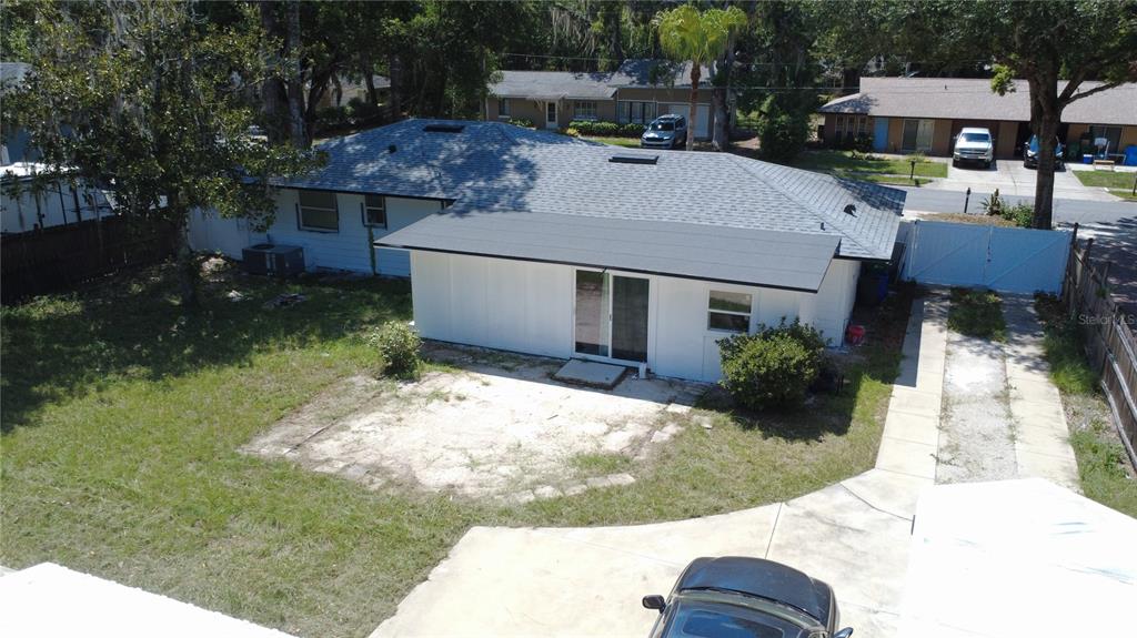 An aerial view shows the back of a white house with a patio and driveway — 925 E 10TH AVENUE, MOUNT DORA, FL