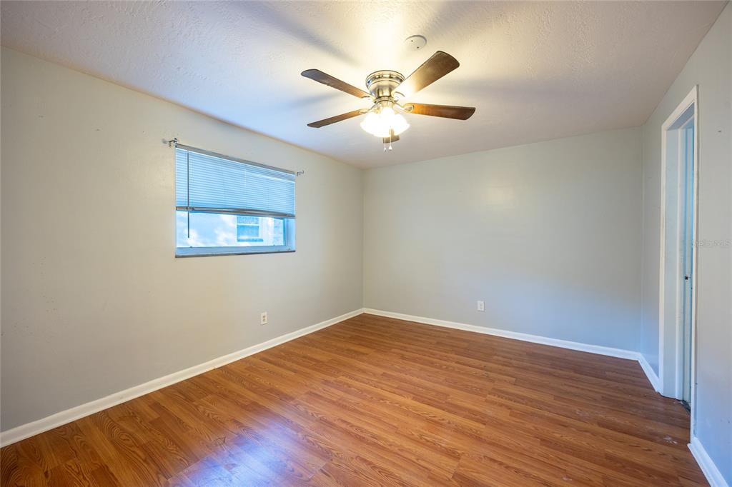 An empty bedroom features light gray walls, wood-look flooring, a ceiling fan, and a window — 400 S METEOR AVENUE, CLEARWATER, FL