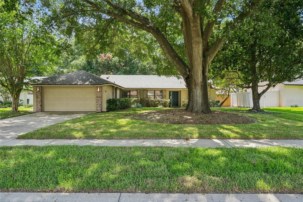 A single-story house with a beige exterior, a two-car garage, and a large front tree — 9433 PALM TREE DRIVE, WINDERMERE, FL