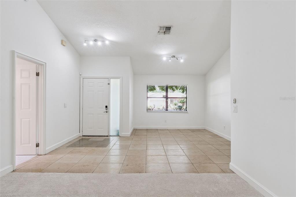 An entryway with tiled floors, a white front door, and a window in a living area — 9433 PALM TREE DRIVE, WINDERMERE, FL
