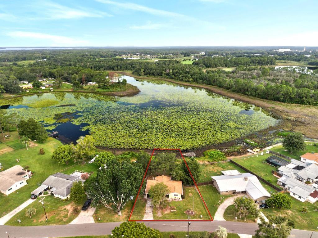 An aerial view shows a single-story house with a fenced backyard bordering a large lake — 37401 TURNER DRIVE, UMATILLA, FL