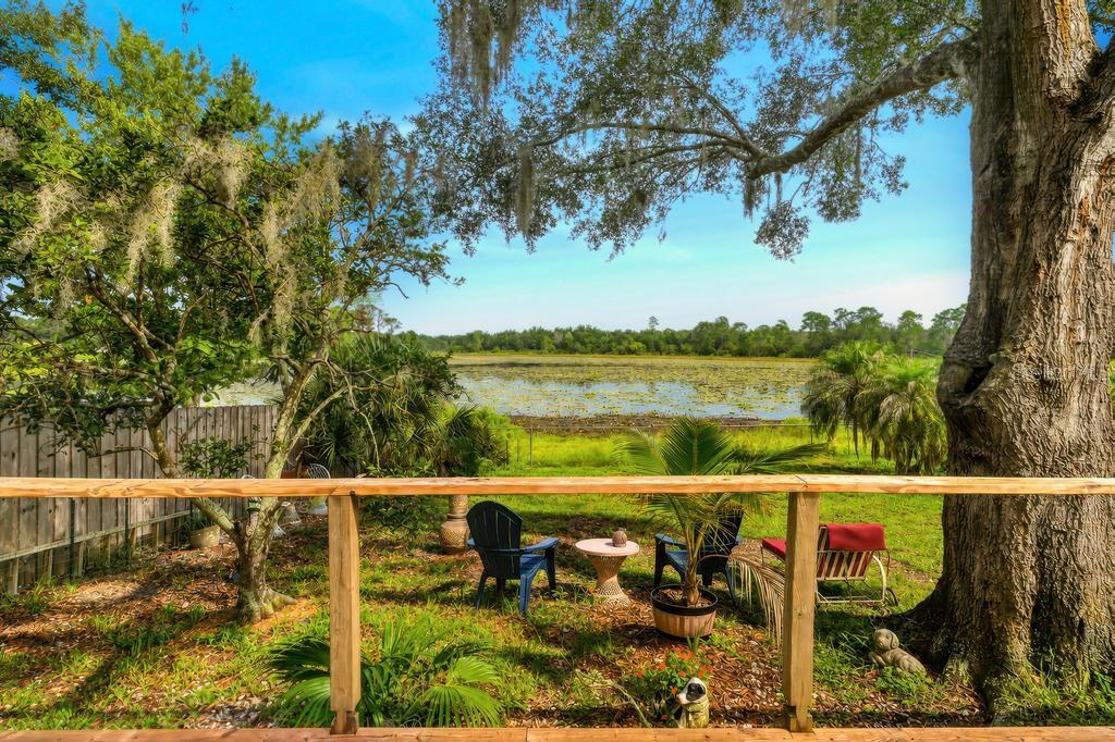 A wooden deck overlooks a grassy yard with chairs, trees, and a pond in the distance — 37401 TURNER DRIVE, UMATILLA, FL