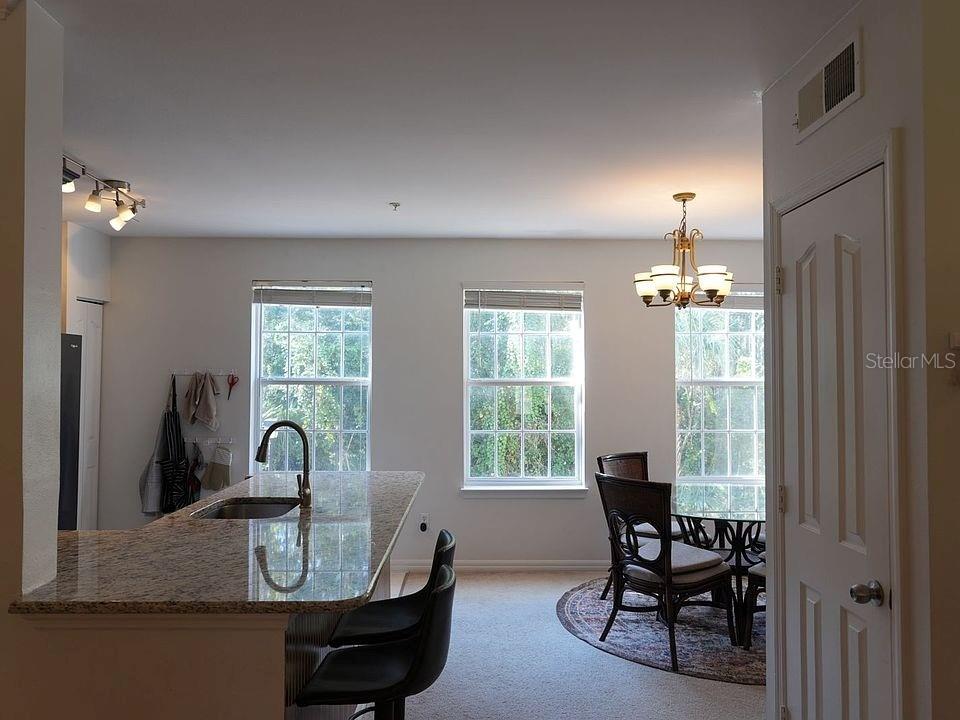 A kitchen with a granite island and a dining area with a chandelier and windows — 1004 WATERSIDE DRIVE UNIT 1004, CELEBRATION, FL