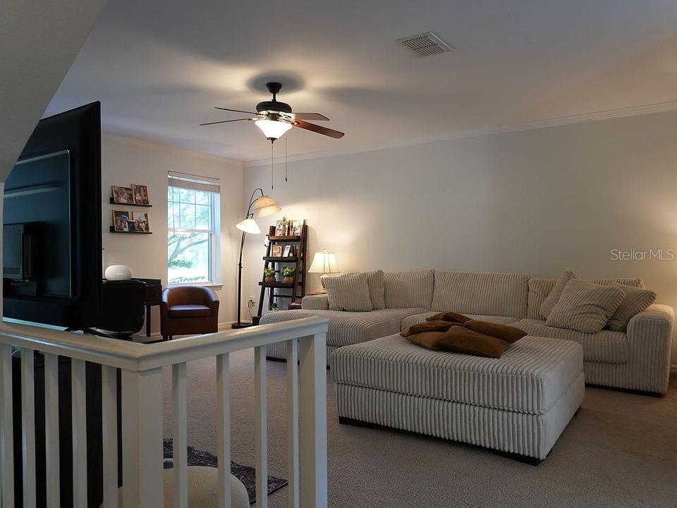 A living room features a large sectional sofa, a matching ottoman, and a ceiling fan — 1004 WATERSIDE DRIVE UNIT 1004, CELEBRATION, FL