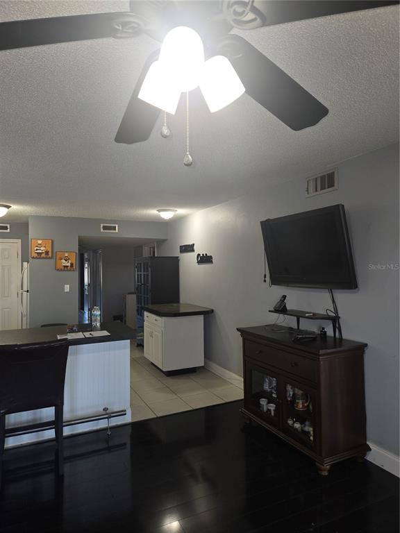 A living room area features a large wine-themed framed print hanging above a black sofa — 6400 46TH AVENUE N UNIT 305, KENNETH CITY, FL