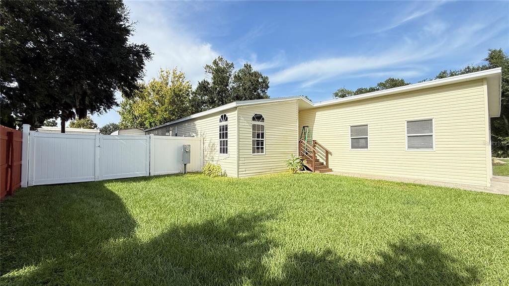 A garage with a concrete floor, exposed wooden ceiling joists, and a rear entry door — 10404 BRUSSELS DRIVE, RIVERVIEW, FL