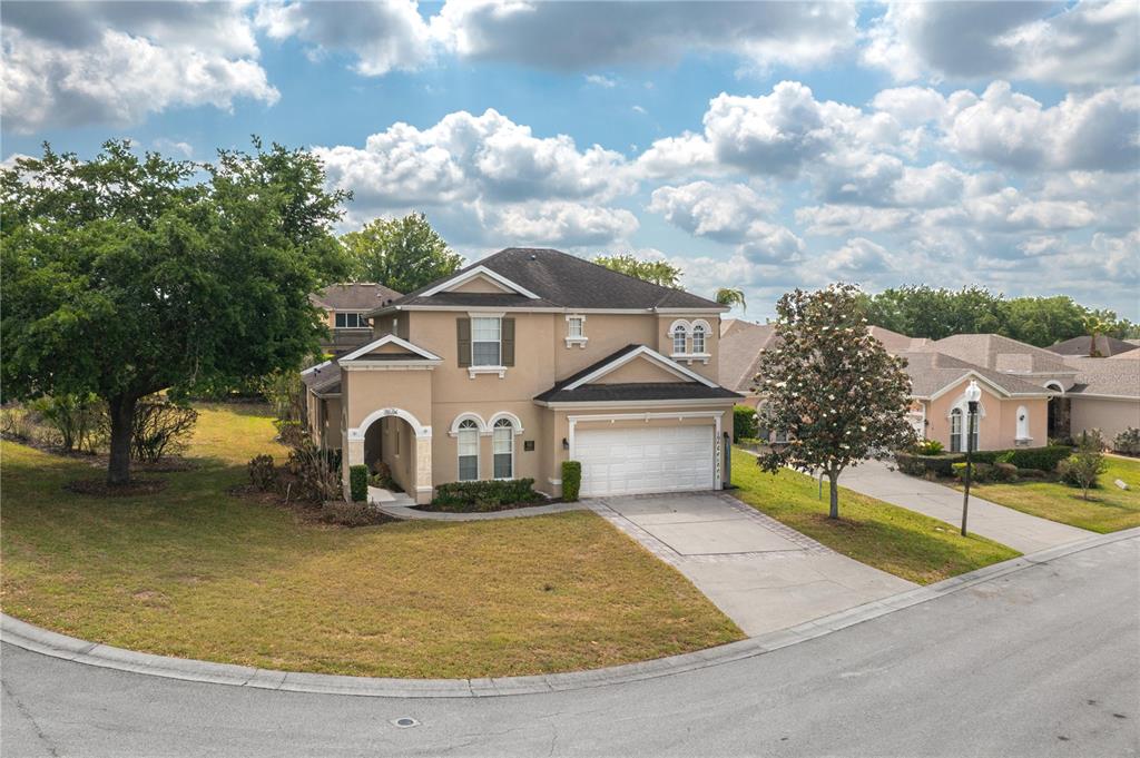 A two-story suburban house with a tan stucco exterior, a two-car garage, and a driveway — 106 SENECA LN, DAVENPORT, FL