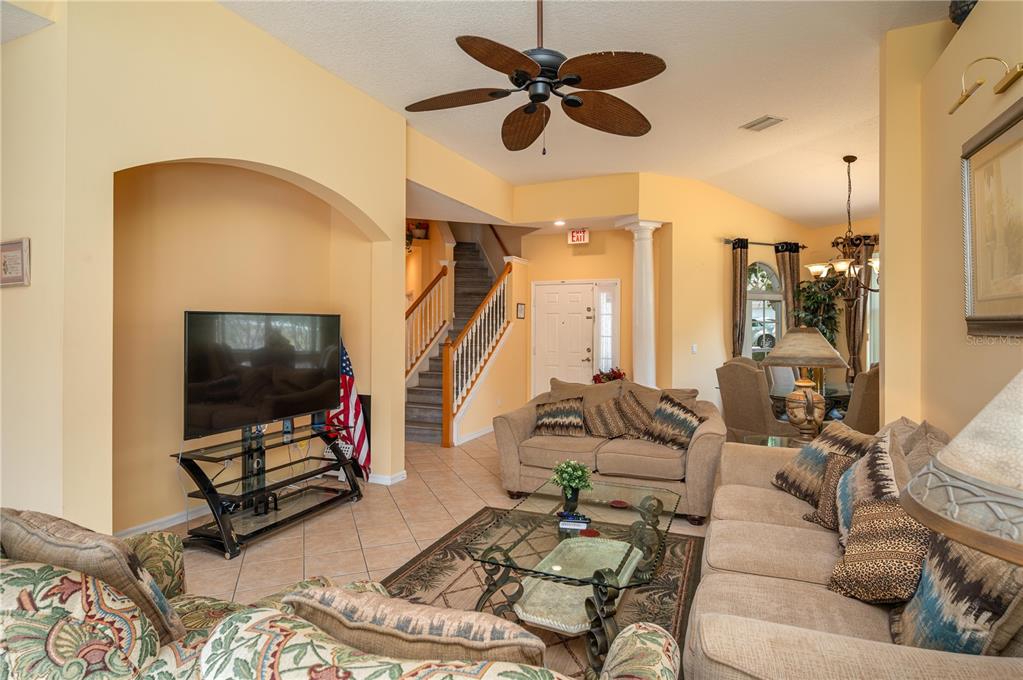 A living room with tile floors, a ceiling fan, a television, and a staircase — 106 SENECA LN, DAVENPORT, FL