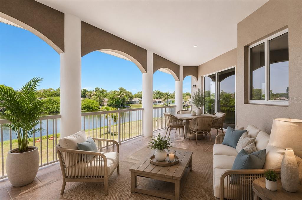 A covered outdoor patio features wicker furniture, a dining set, and views of a lake — 8335 CHEYENNE DRIVE, SEMINOLE, FL