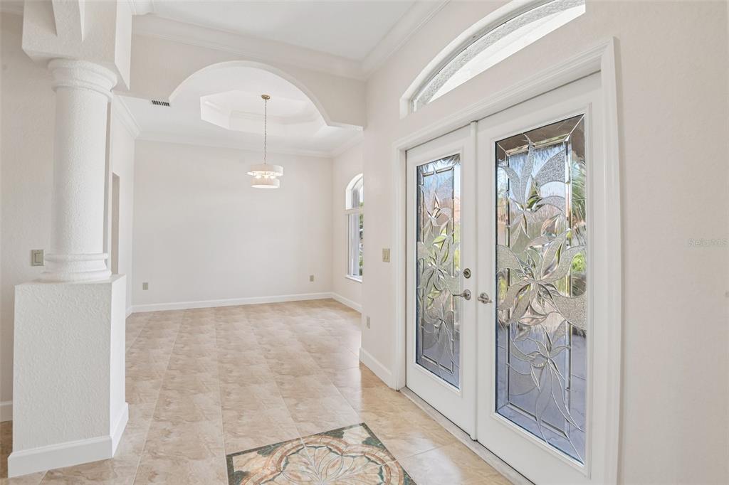 An entryway with tile flooring, a decorative inlay, and double doors with glass floral inserts — 8335 CHEYENNE DRIVE, SEMINOLE, FL