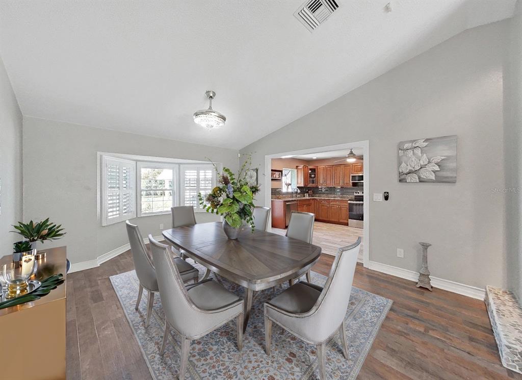 A dining room with a wooden table, six chairs, and a view into the kitchen — 438 LAFAYETTE BOULEVARD, OLDSMAR, FL