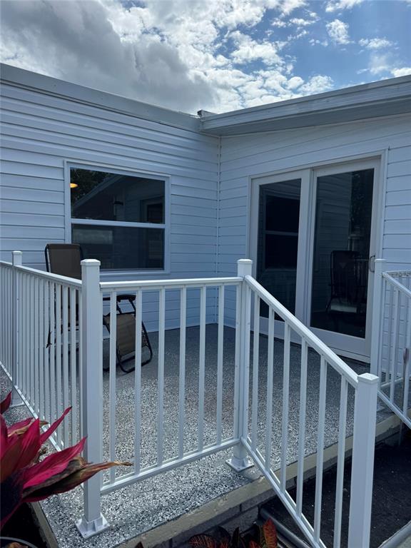 A white-sided exterior features a small concrete patio enclosed by a white metal railing — 10374 106TH AVENUE UNIT 9, LARGO, FL