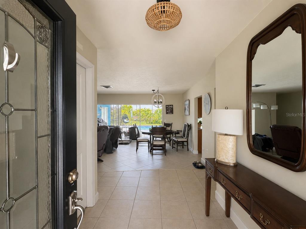 An entryway with tile flooring leads to a dining area and a view of a pool — 1009 INDIAN HILLS COURT, VENICE, FL
