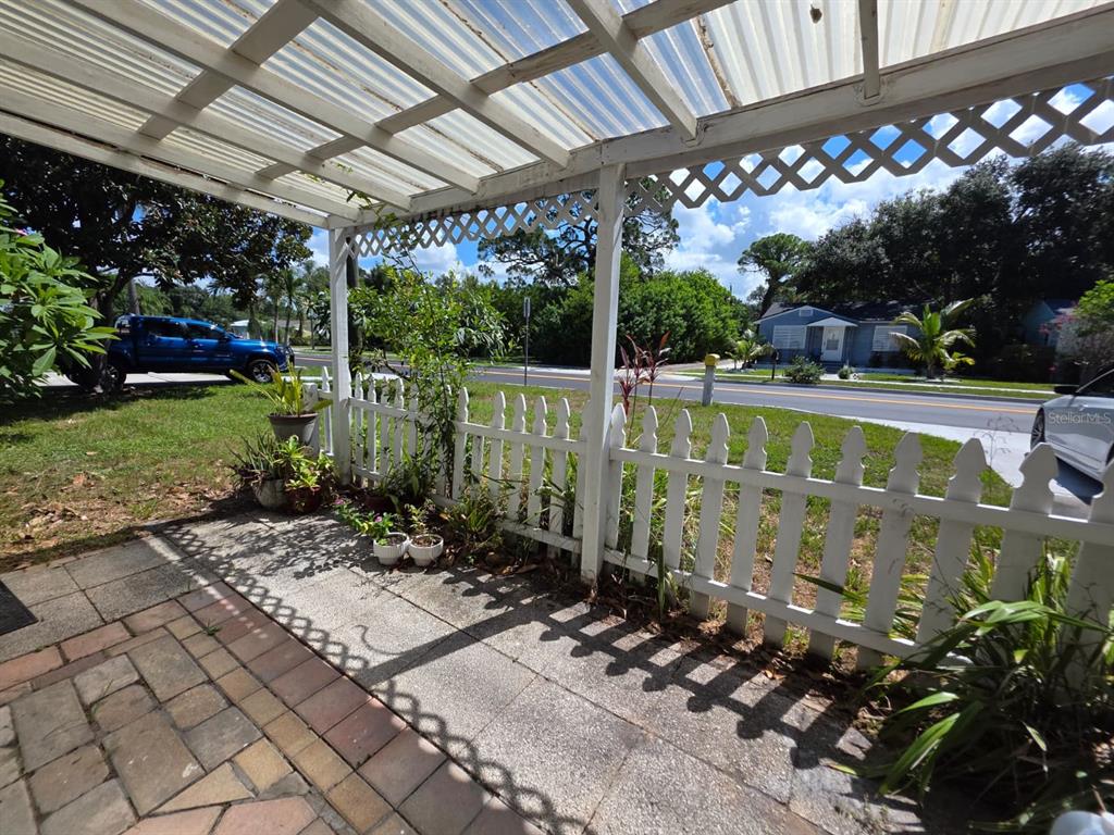 A covered patio with a white picket fence overlooks a street and a neighboring house — 2015 58TH STREET S, GULFPORT, FL