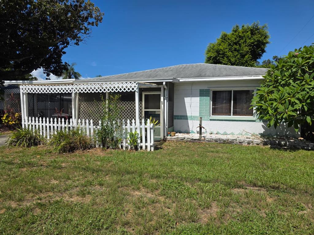 A single-story house with a screened porch, white picket fence, and light-colored block exterior — 2015 58TH STREET S, GULFPORT, FL