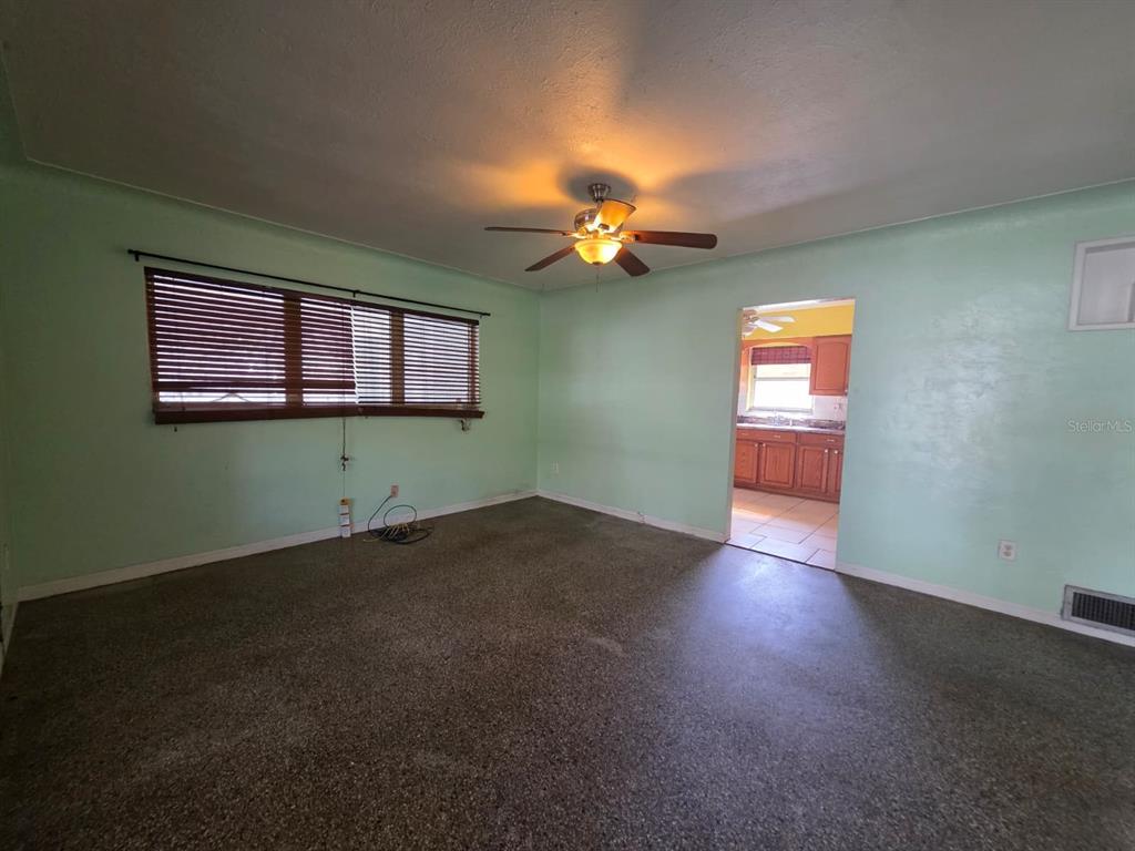 An empty room with mint green walls, a ceiling fan, and dark speckled flooring — 2015 58TH STREET S, GULFPORT, FL