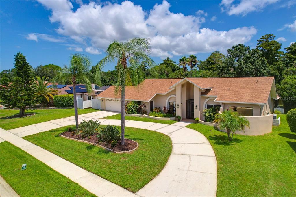 A single-story house with a tan exterior, brown roof, and a curved concrete driveway — 80 FOXFIRE LANE, OLDSMAR, FL