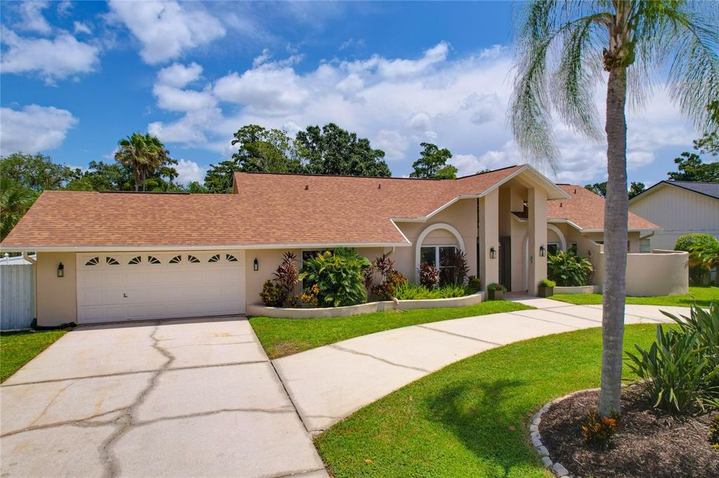 A single-story house with a two-car garage, arched entryway, and a palm tree in front — 80 FOXFIRE LANE, OLDSMAR, FL
