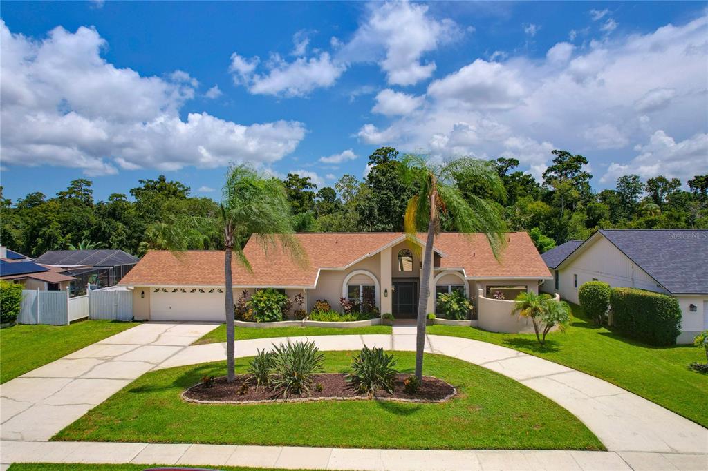 A single-story house with a tan exterior, brown roof, and a curved driveway with palms — 80 FOXFIRE LANE, OLDSMAR, FL