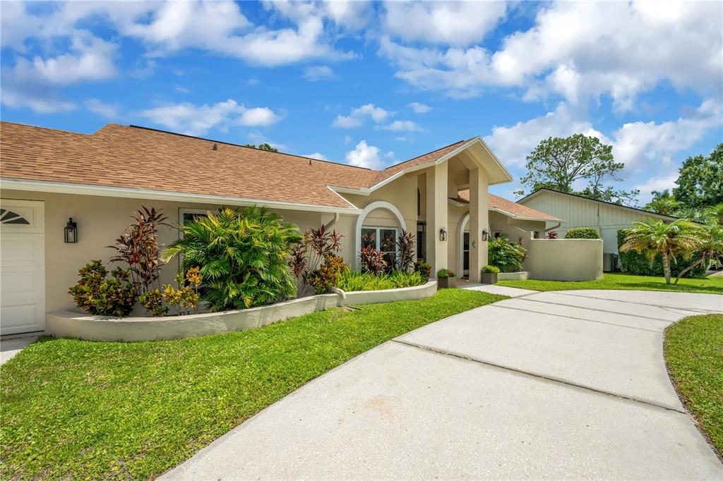 A single-story house with a beige exterior, a tan shingled roof, and a concrete driveway — 80 FOXFIRE LANE, OLDSMAR, FL