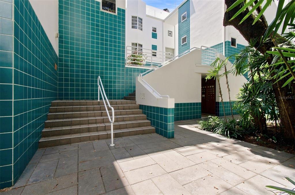 An outdoor staircase with a white railing leads to a building entrance with teal tiles — 4950 BAYSHORE BLVD UNIT 8, TAMPA, FL