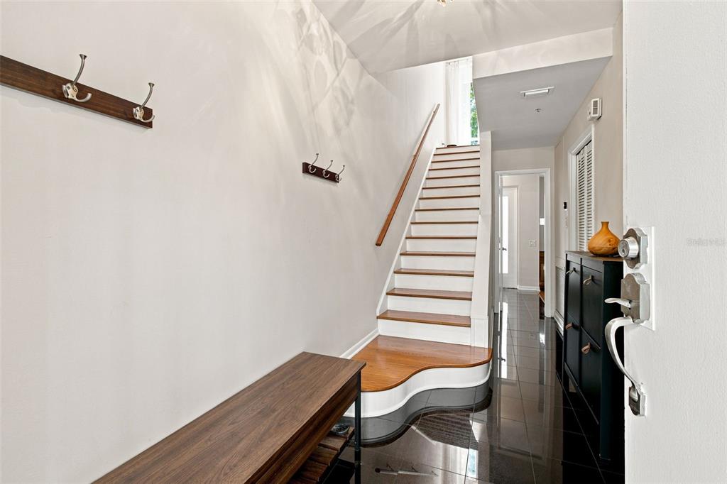 An entryway features a wooden staircase, dark tile flooring, a bench, and wall-mounted coat hooks — 4950 BAYSHORE BLVD UNIT 8, TAMPA, FL