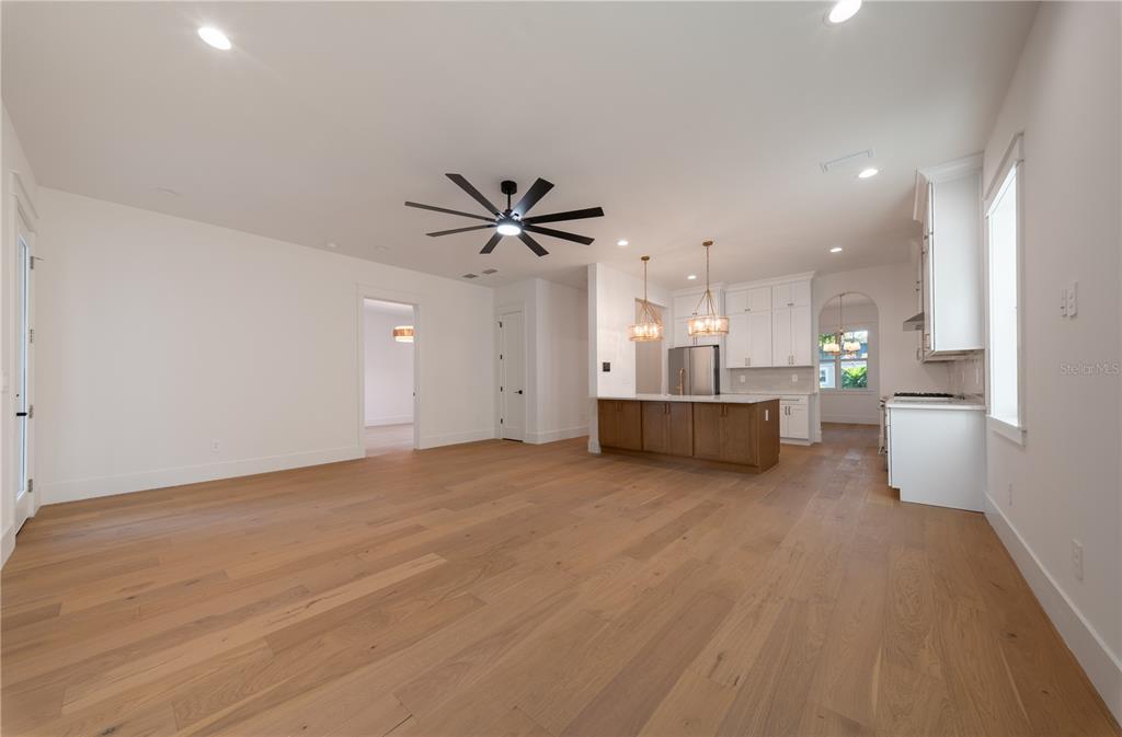 An open-concept kitchen and living area features light wood flooring, white cabinetry, and a kitchen island — 1200 13TH STREET N, ST PETERSBURG, FL