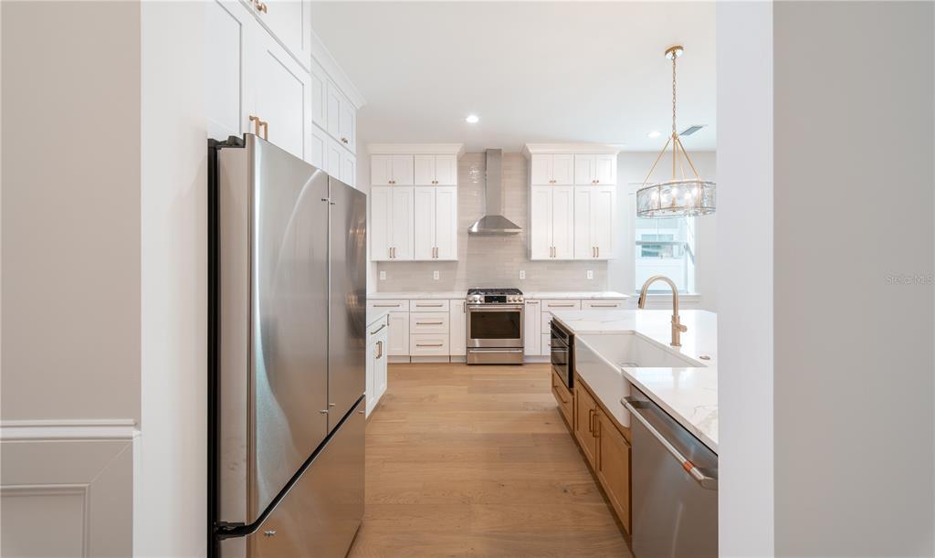 A modern kitchen features white cabinetry, stainless steel appliances, a farmhouse sink, and wood flooring — 1200 13TH STREET N, ST PETERSBURG, FL