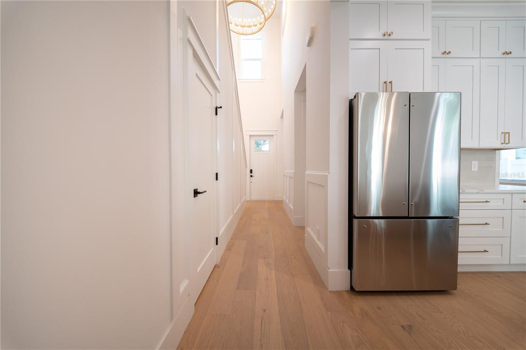 A hallway with light wood floors leads to a white door under a tall ceiling — 1200 13TH STREET N, ST PETERSBURG, FL