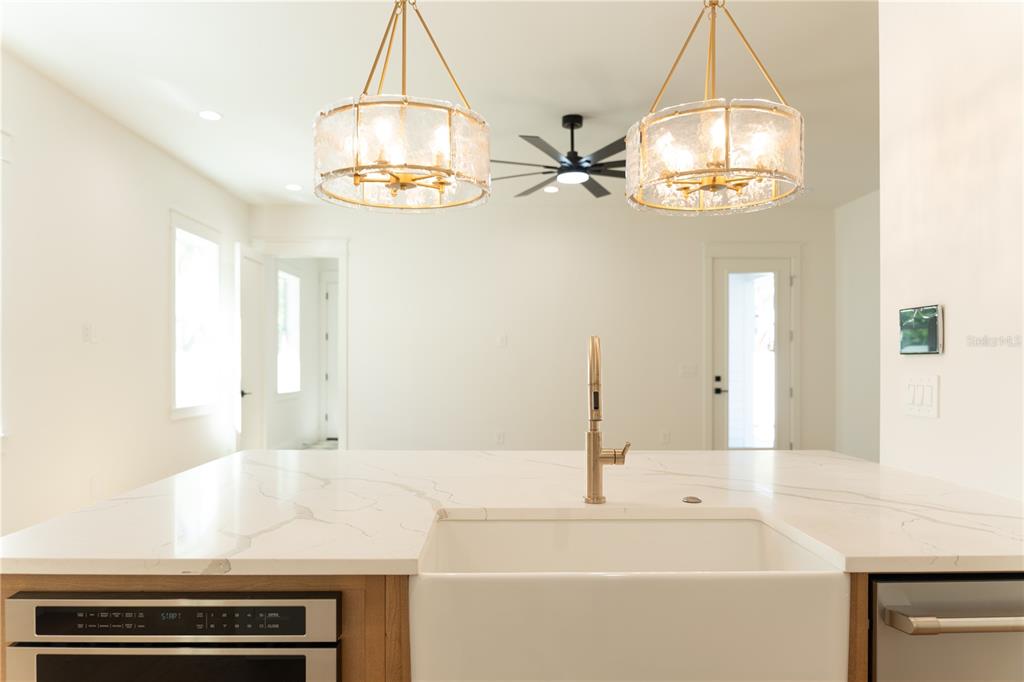 A kitchen island with a farmhouse sink and gold faucet sits beneath two glass chandeliers — 1200 13TH STREET N, ST PETERSBURG, FL