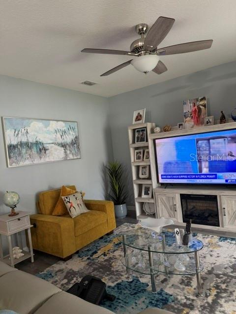 A living room features a yellow armchair, a glass coffee table, and a television console — 9934 LENOX STREET, CLERMONT, FL