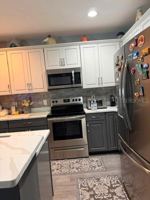A kitchen features white upper cabinets, dark lower cabinets, stainless steel appliances, and a central island — 9934 LENOX STREET, CLERMONT, FL