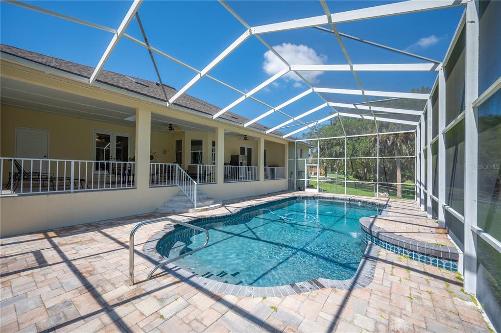 An aerial view shows a house with a screened pool, a driveway, and surrounding trees — 6617 POLEY CREEK DRIVE W, LAKELAND, FL