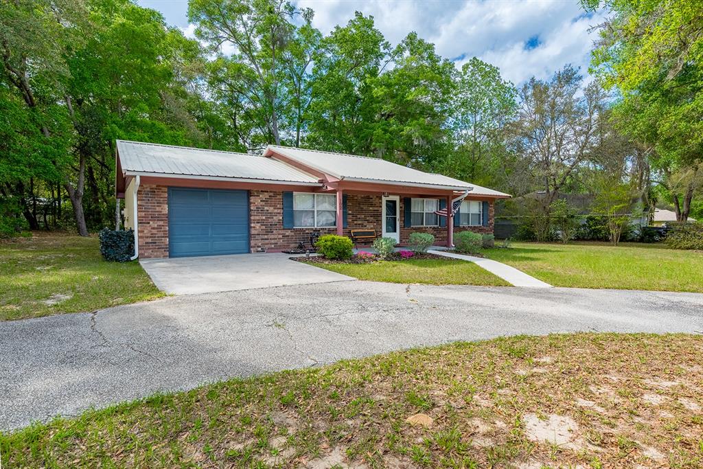 A single-story brick house with a metal roof and an attached garage sits on a lot — 102 SWANS NEST CIRCLE, MELROSE, FL