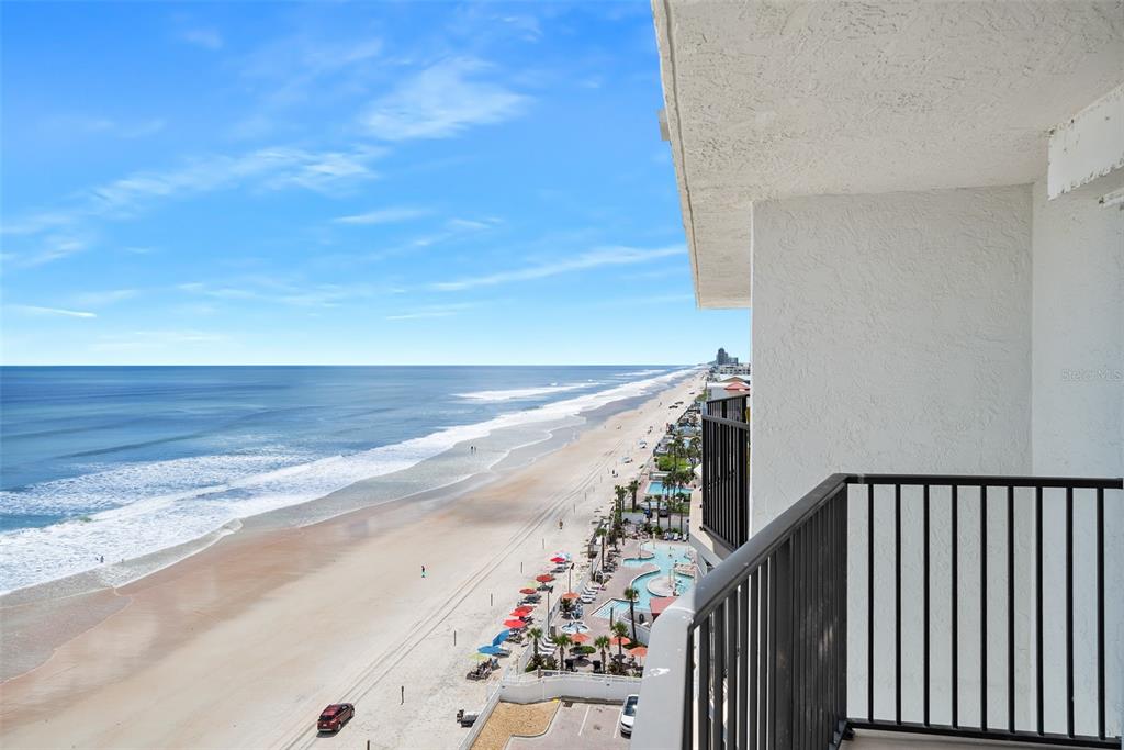 A high-angle view of a beach and ocean from a balcony with a black railing — 111 S ATLANTIC AVENUE UNIT 1104, ORMOND BEACH, FL