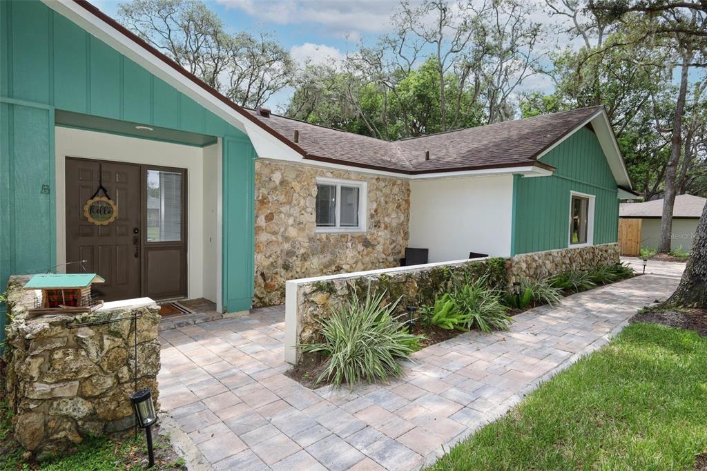 A teal-sided house with a stone facade and a paved walkway leading to the entrance — 1015 ANTELOPE TRAIL, WINTER SPRINGS, FL