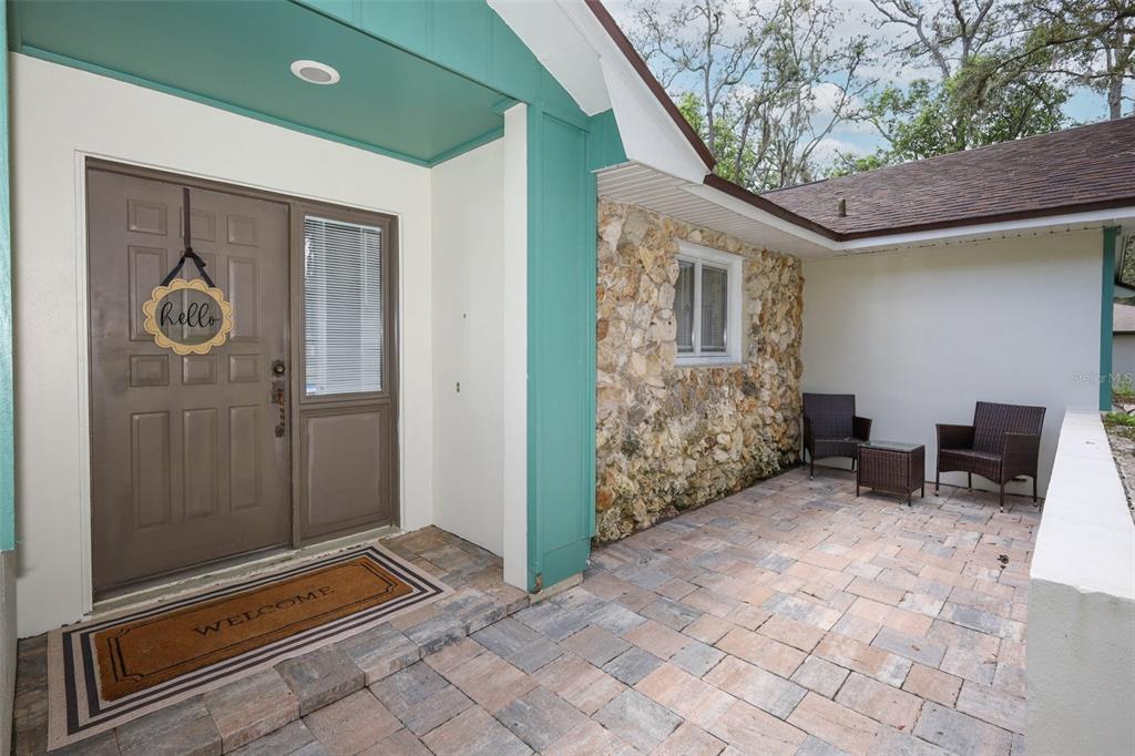 A paved patio leads to a brown front door with a side light and stone siding — 1015 ANTELOPE TRAIL, WINTER SPRINGS, FL