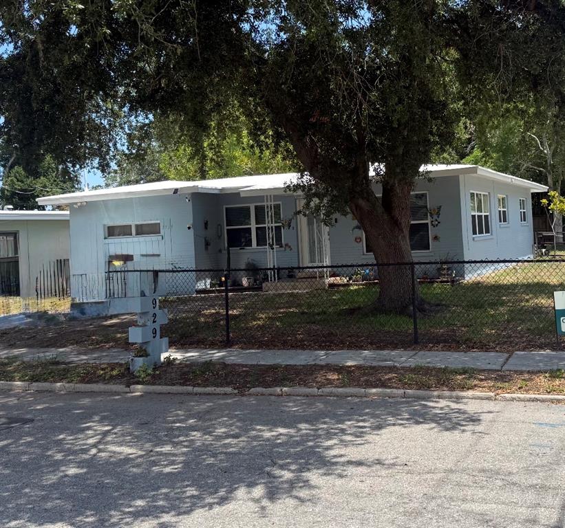 A light blue single-story house with a white roof sits behind a chain-link fence — 1929 3RD AVENUE E, BRADENTON, FL