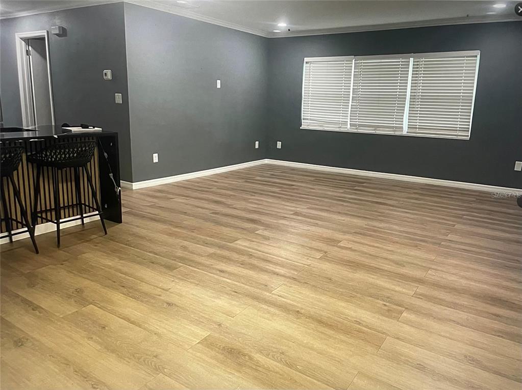 An open living area features dark gray walls, light wood-look flooring, and a kitchen island — 1929 3RD AVENUE E, BRADENTON, FL