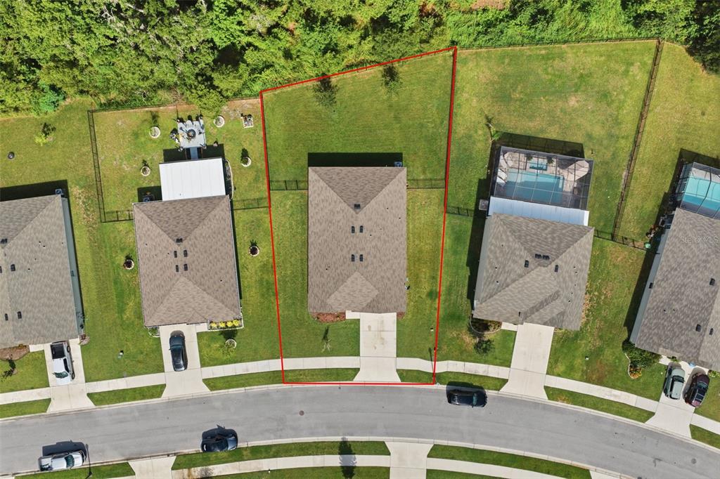 An aerial view shows a single-family home with a fenced backyard on a curved street — 5015 CADIZ COURT, BROOKSVILLE, FL