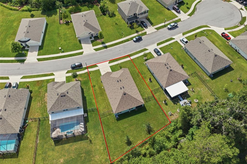 An aerial view shows a single-family house with a fenced backyard outlined in red — 5015 CADIZ COURT, BROOKSVILLE, FL