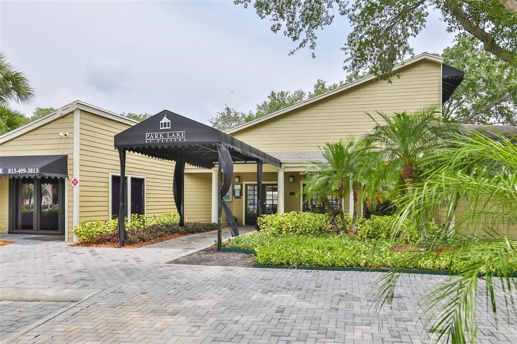The exterior of a tan building features a black awning over the entrance walkway — 215 LAKE BROOK CIRCLE UNIT 204, BRANDON, FL