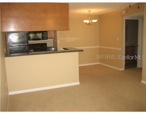 A kitchen with a breakfast bar overlooks a dining area with a chandelier and carpet — 215 LAKE BROOK CIRCLE UNIT 204, BRANDON, FL