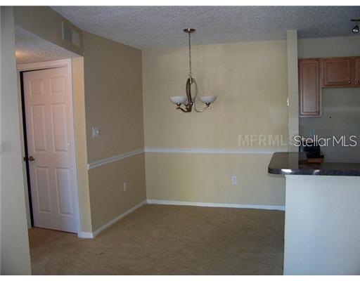 A dining area features beige walls, a chandelier, carpeted flooring, and a doorway — 215 LAKE BROOK CIRCLE UNIT 204, BRANDON, FL