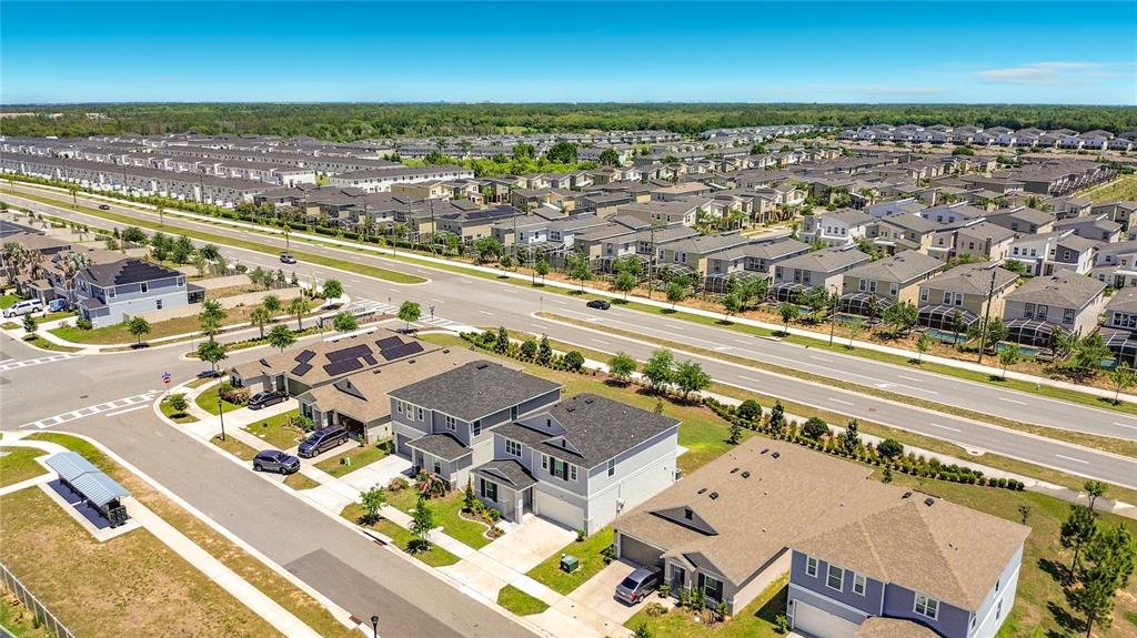An aerial view shows a suburban neighborhood with houses, streets, and solar panels — 795 OVERPOOL AVENUE, DAVENPORT, FL