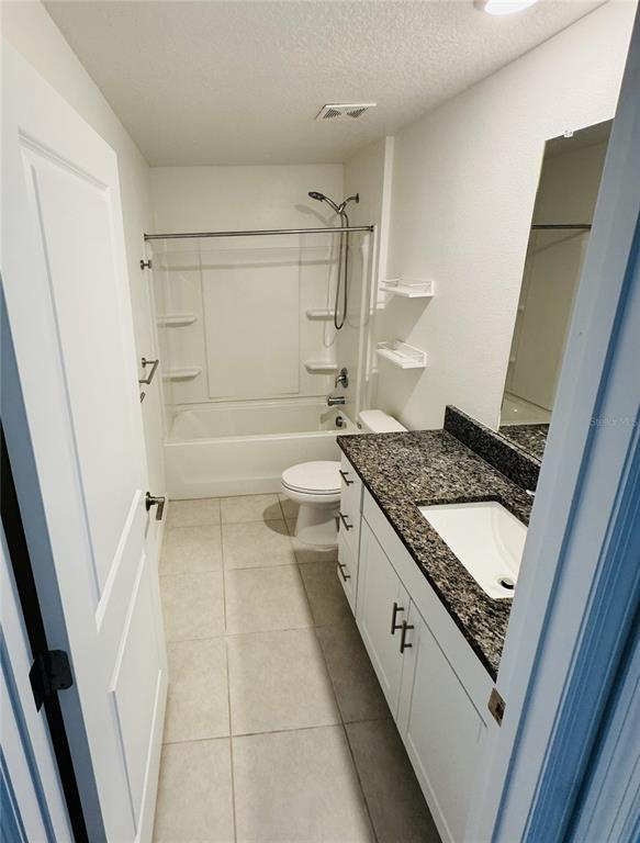 A bathroom features a white vanity with a granite countertop, a toilet, and a tub-shower — 13181 GARNET RASPBERRY AVENUE, WIMAUMA, FL